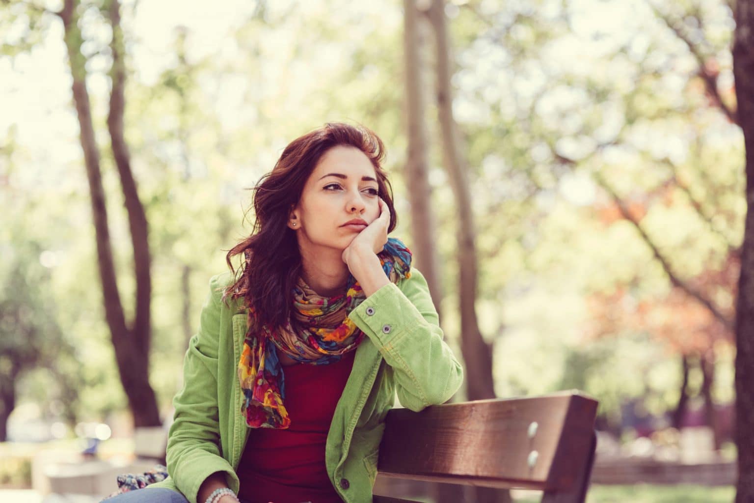 Nose-Loss-of-Smell Woman sitting on a park bench with an uninterested expression.